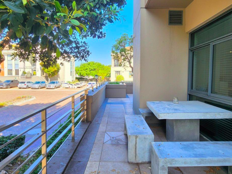 A paved outdoor balcony area featuring a metal balustrade and direct access to the office building exterior.