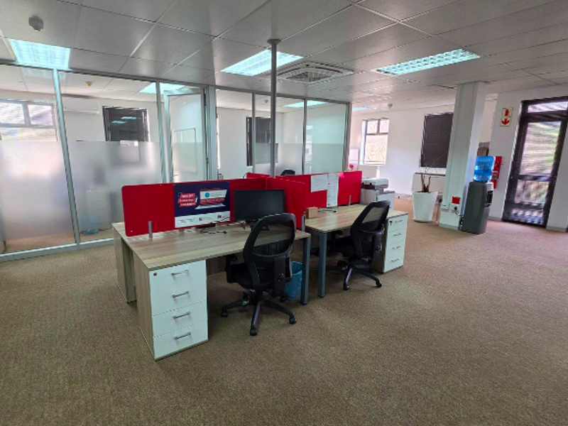 Open-plan office space featuring glass partitions, suspended ceilings with recessed lighting, and carpeted flooring, providing a professional and functional work environment.