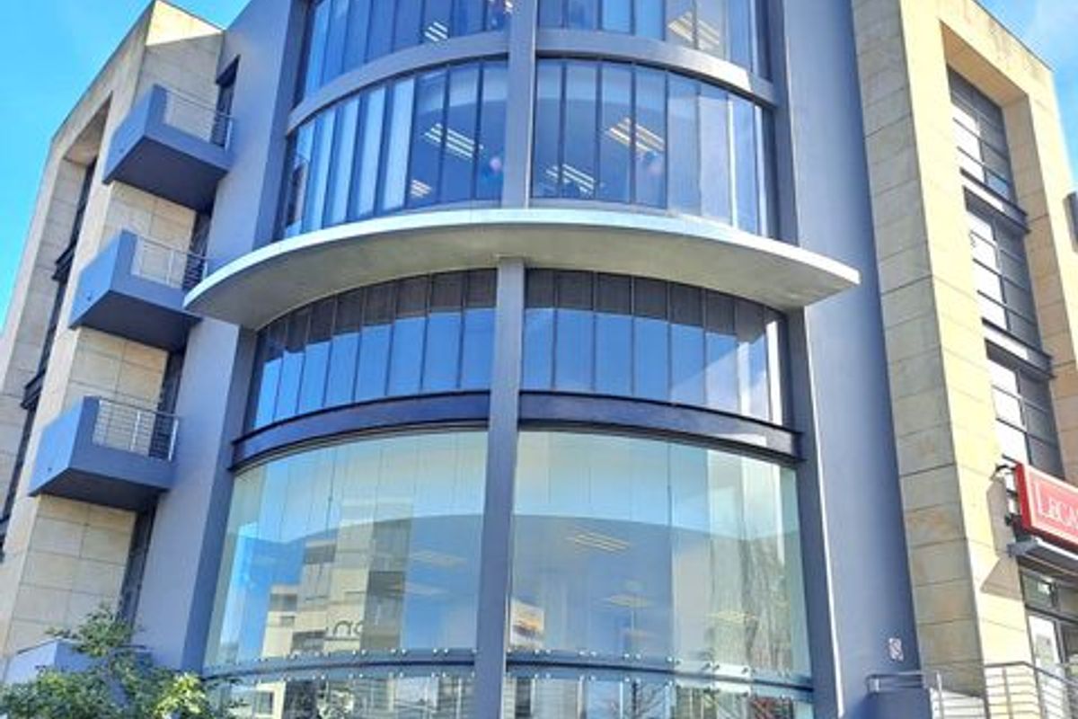 Modern multi-story office building facade featuring extensive glass curtain walling, prominent signage, and integrated balconies.