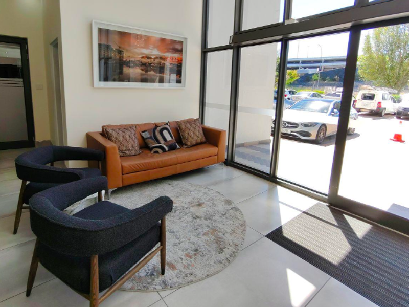 Modern office entrance lobby featuring large glass sliding doors, tiled flooring, and a bright, welcoming reception area.