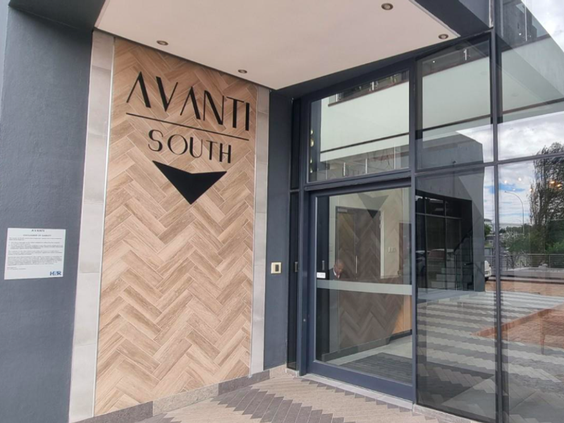 Modern office building entrance featuring a glass facade and decorative herringbone tile wall cladding with integrated signage.