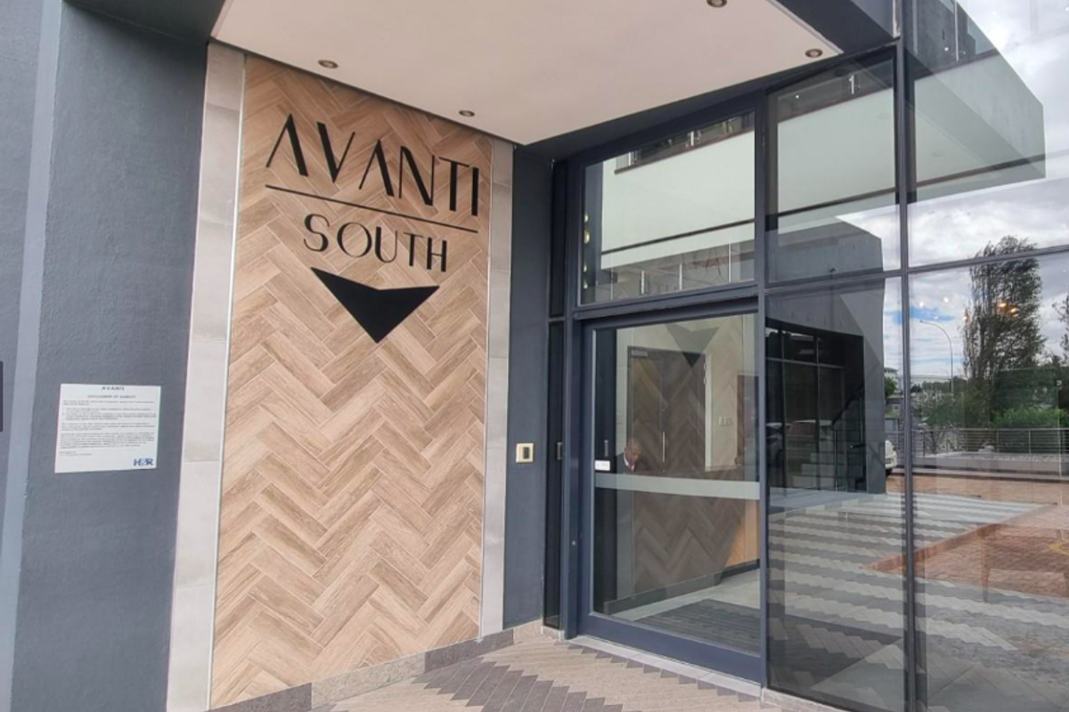 Modern office building entrance featuring a glass facade and decorative herringbone tile wall cladding with integrated signage.