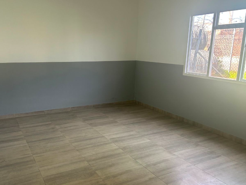 A clean, empty office space featuring neutral two-tone wall paint and modern tiled flooring, suitable for a variety of industrial or commercial uses.