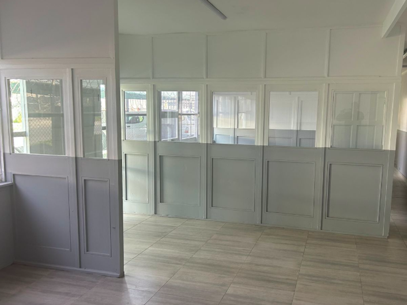 An open-plan office space featuring neutral-toned partition walls with glass inserts and modern tiled flooring, providing a clean and functional workspace environment.