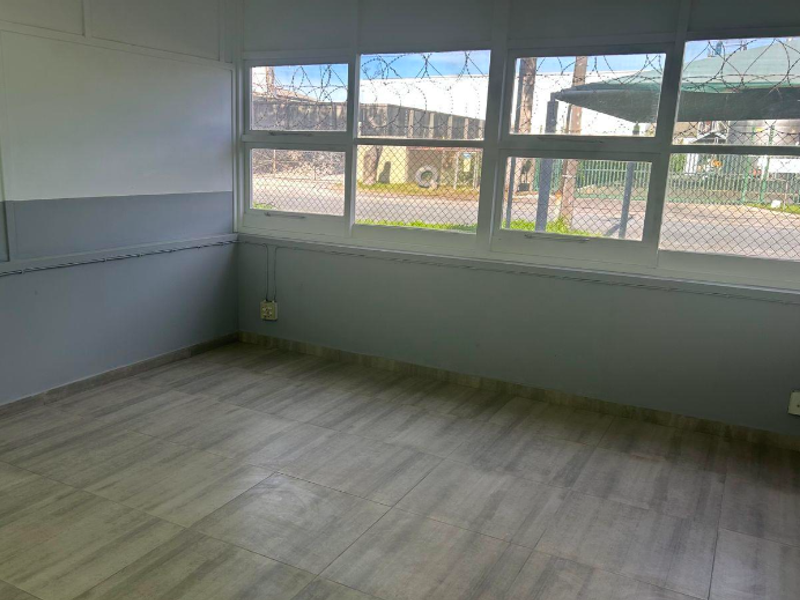 A clean, empty office space featuring large windows, tiled flooring, and functional electrical infrastructure, suitable for a professional workspace.