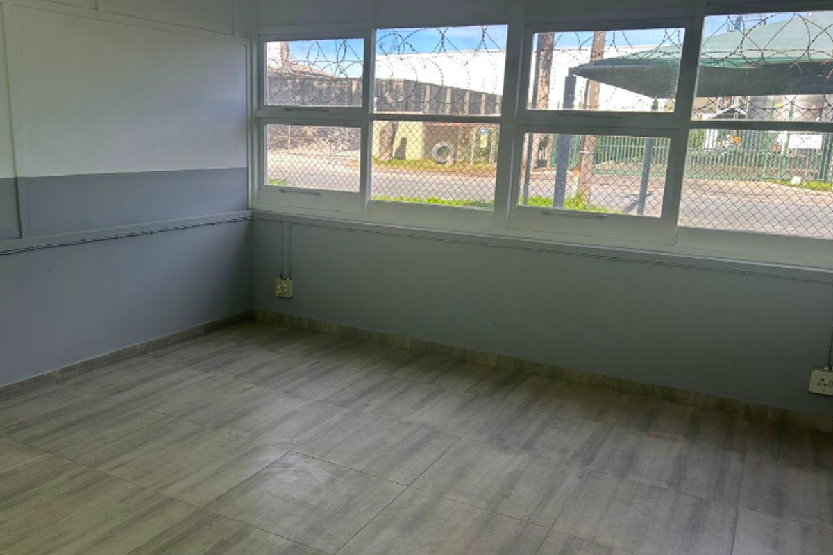 A clean, empty office space featuring large windows, tiled flooring, and functional electrical infrastructure, suitable for a professional workspace.