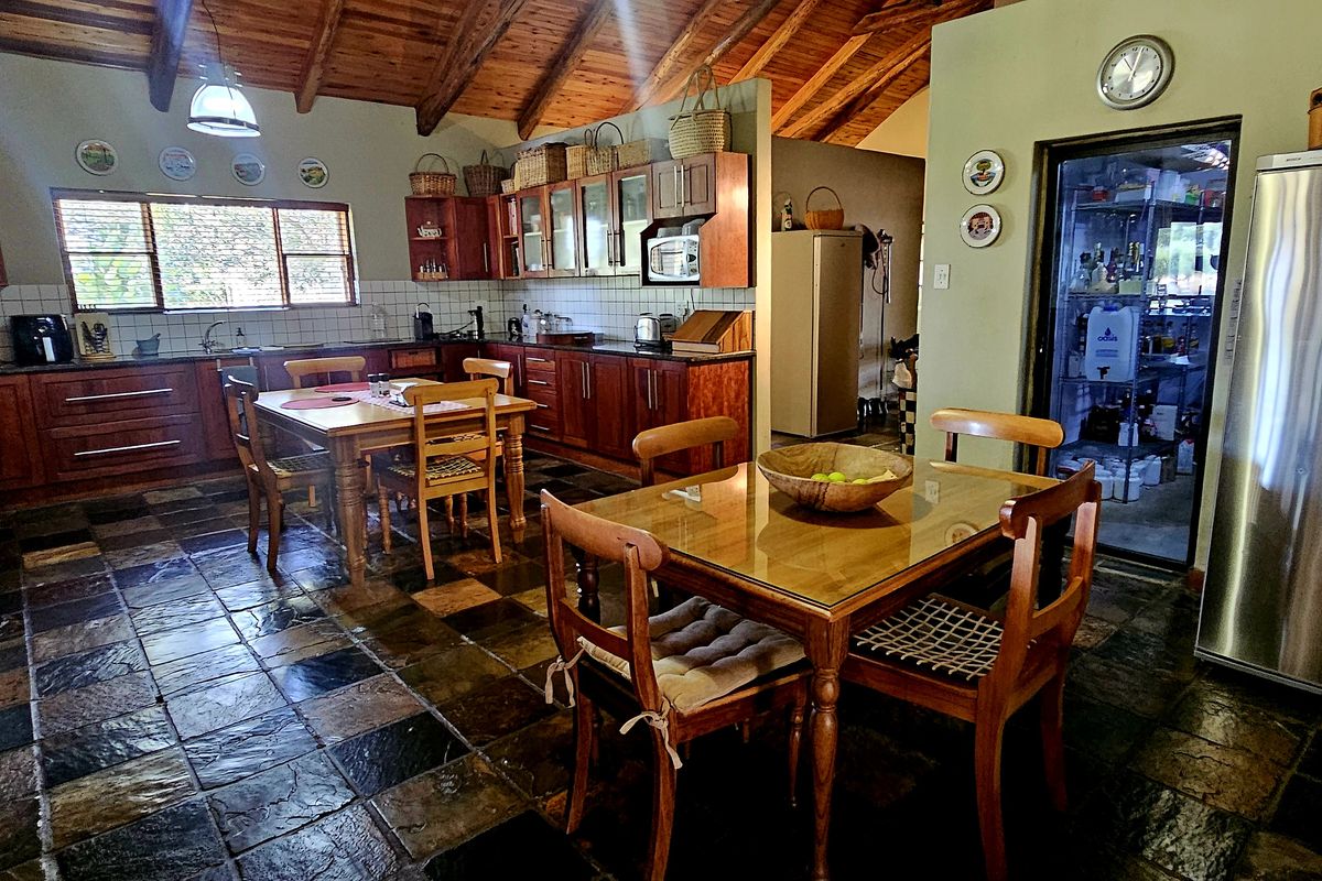 Spacious farmhouse-style kitchen featuring exposed timber beams, slate flooring, extensive wooden cabinetry, granite countertops, and a convenient walk-in pantry.