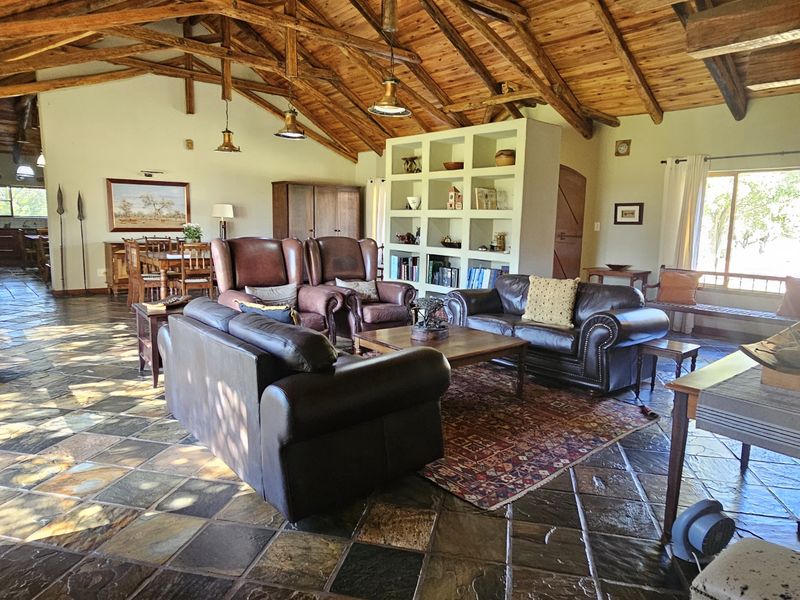 Spacious open-plan living area featuring high vaulted ceilings with exposed timber trusses and durable slate tile flooring throughout.