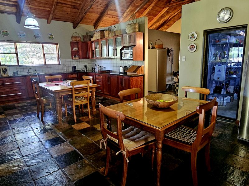 Spacious farmhouse-style kitchen featuring exposed timber beams, slate flooring, extensive wooden cabinetry, granite countertops, and a convenient walk-in pantry.