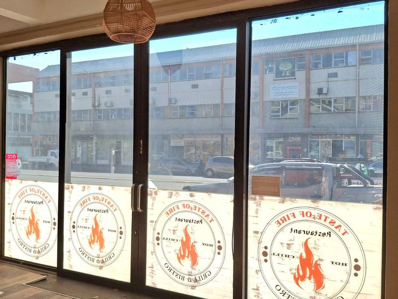 Bright retail entrance area featuring large glass sliding doors, recessed ceiling details, and a modern pendant light fixture.