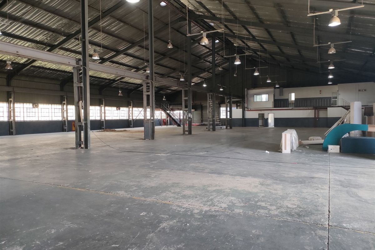 Spacious industrial warehouse featuring high ceilings, steel portal frame construction, concrete flooring, and ample natural light through large industrial windows.
