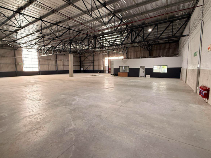 Spacious industrial warehouse featuring high ceilings with exposed steel trusses, polished concrete flooring, and integrated fire safety systems.