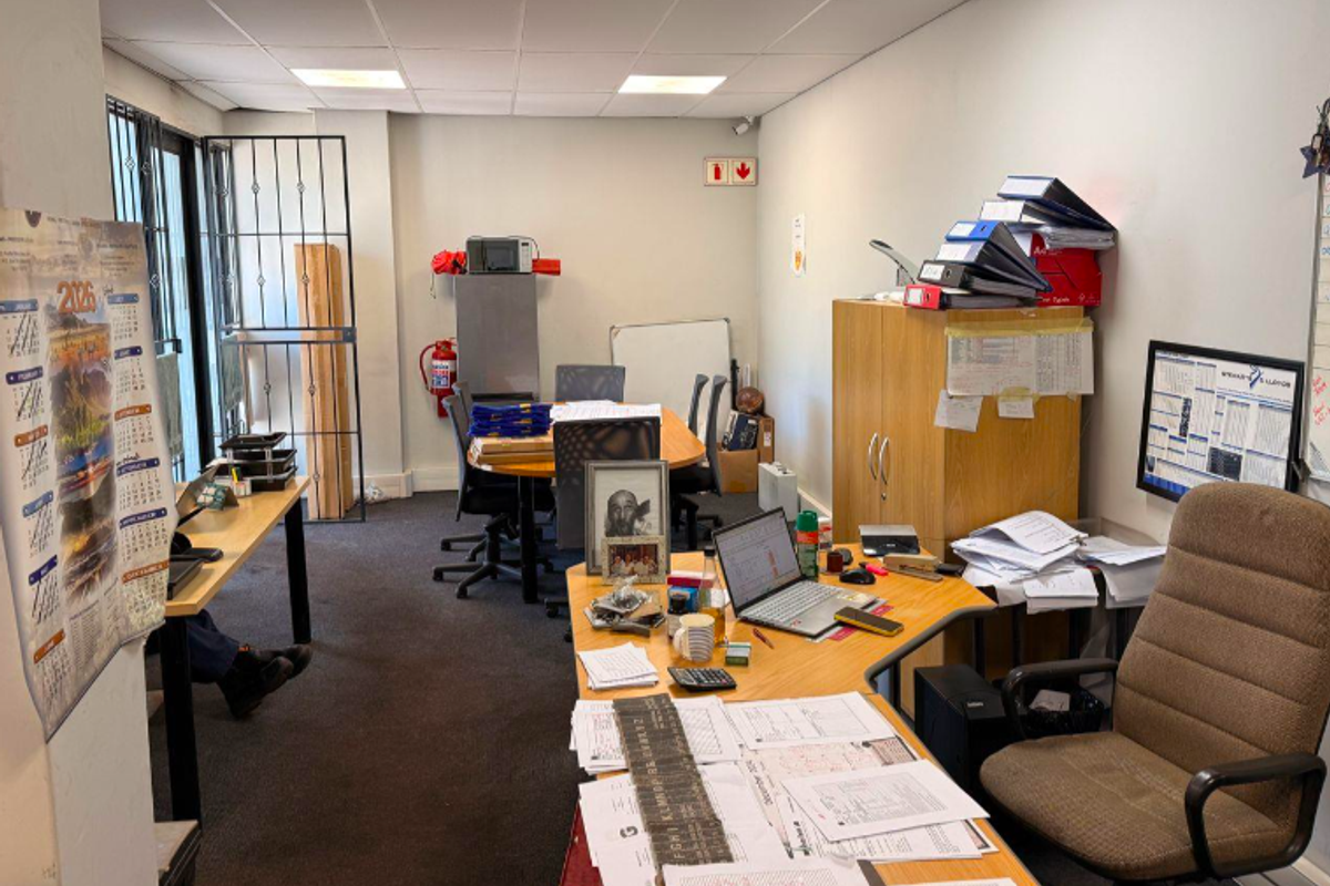 A functional office space featuring a suspended ceiling, security gate, and fire safety equipment, suitable for administrative or industrial business operations.