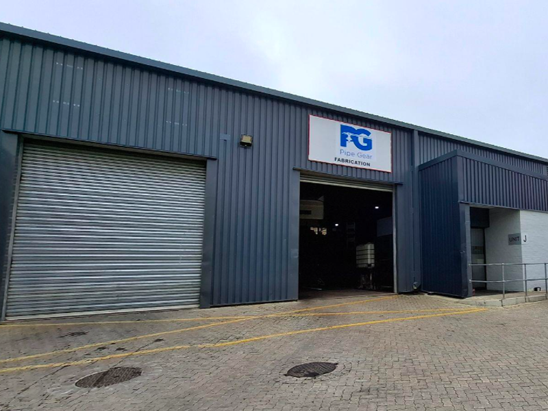 Industrial unit exterior featuring corrugated metal cladding, a large roller shutter door, and paved driveway access.