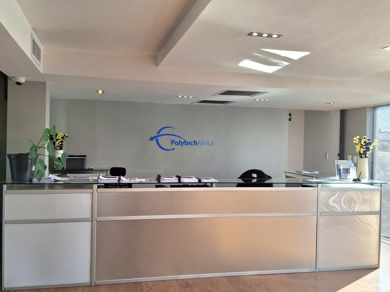 Professional industrial reception area featuring a modern built-in desk, recessed lighting, and clean laminate flooring.
