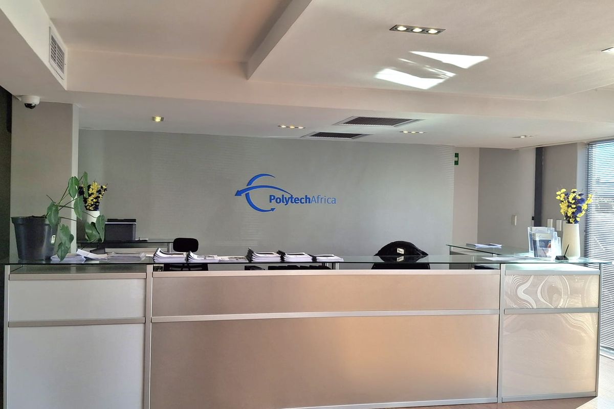 Professional industrial reception area featuring a modern built-in desk, recessed lighting, and clean laminate flooring.