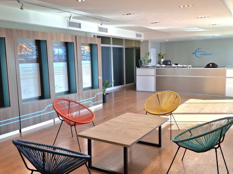 A modern, professional industrial office reception area featuring a sleek reception desk, recessed lighting, and high-quality laminate flooring.