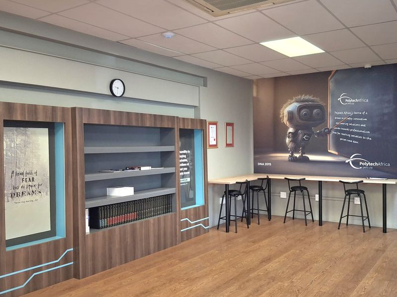 Modern office space featuring a built-in desk, custom shelving, laminate flooring, and a ceiling-mounted cassette air conditioning unit.