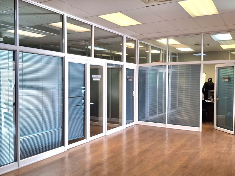 Modern office space featuring high-quality aluminium and glass partitioning, laminate flooring, and integrated ceiling-mounted air conditioning.
