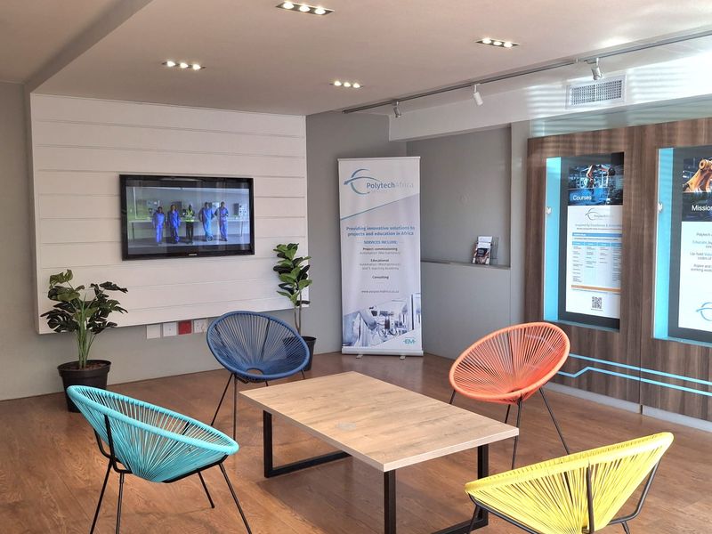 A modern office reception or breakout area featuring recessed lighting, wood-look flooring, and integrated display cabinetry for professional use.