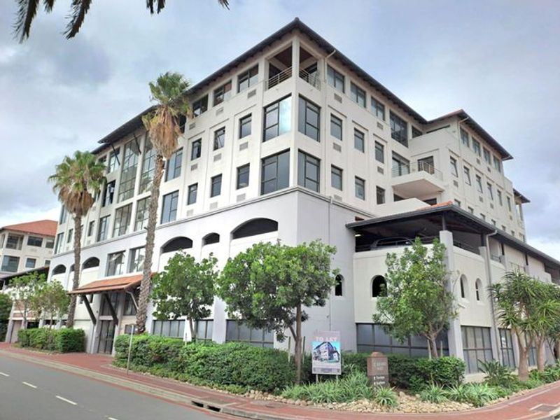 A multi-story commercial office building featuring a modern facade, balconies, and integrated covered parking facilities.