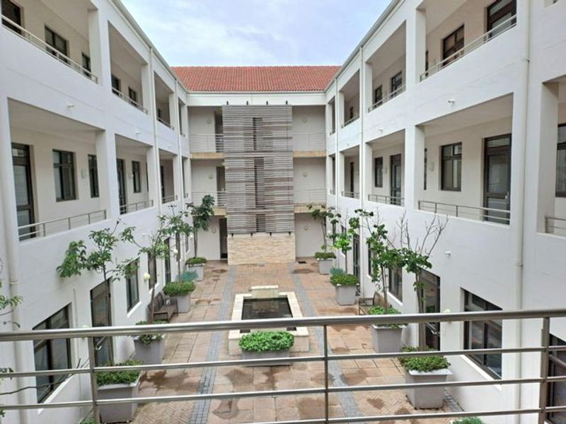 A well-maintained central courtyard featuring a water feature, paved walkways, and multi-level office balconies with stainless steel railings.