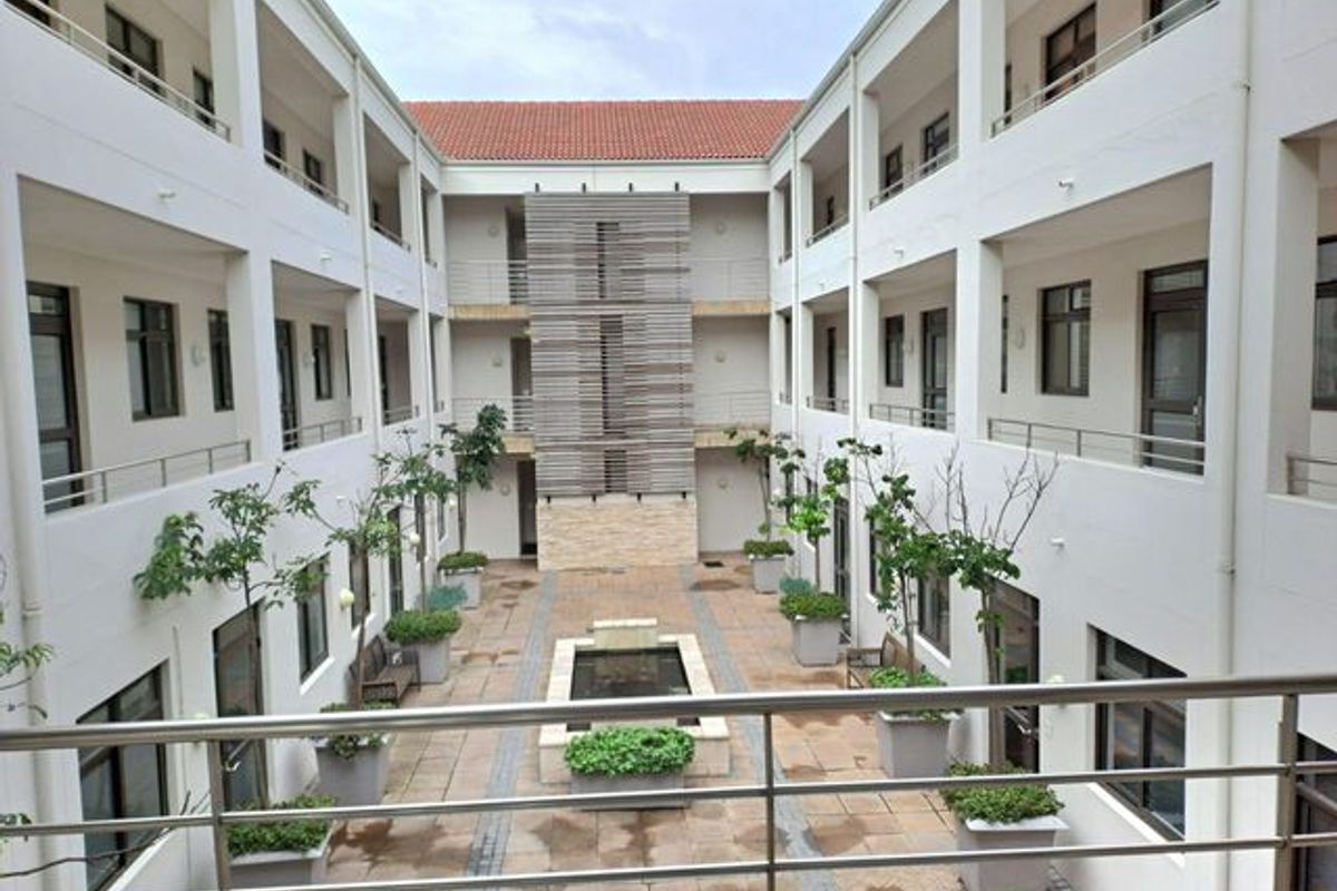 A well-maintained central courtyard featuring a water feature, paved walkways, and multi-level office balconies with stainless steel railings.