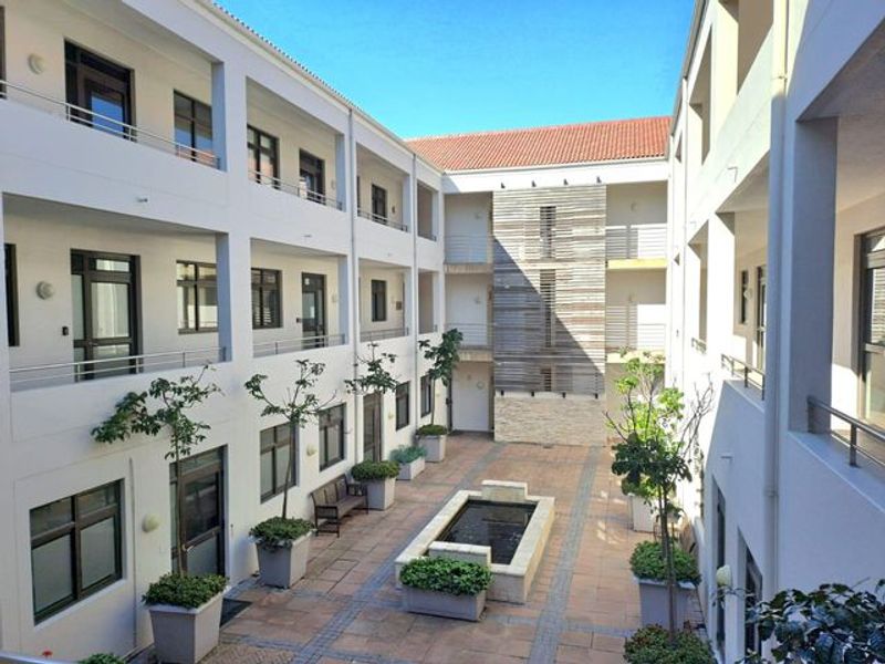 A well-maintained central courtyard featuring a stone water feature, paved walkways, and multi-level office balconies with modern architectural finishes.