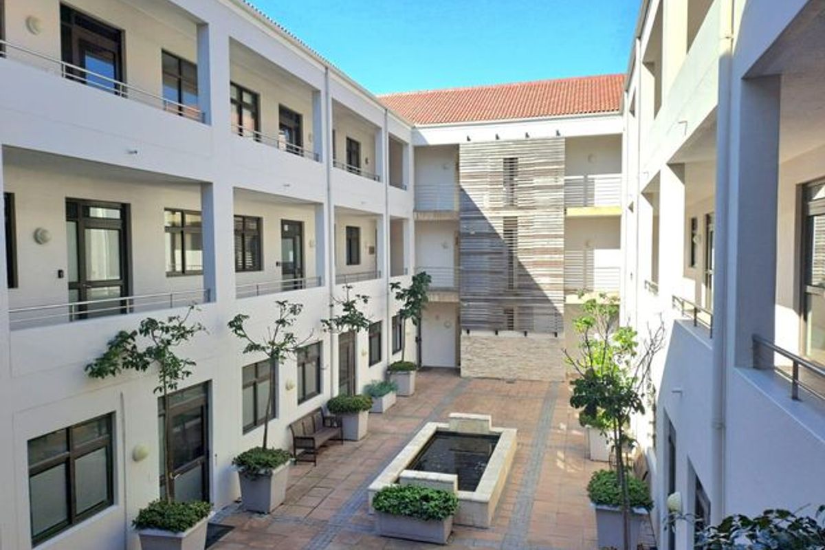A well-maintained central courtyard featuring a stone water feature, paved walkways, and multi-level office balconies with modern architectural finishes.