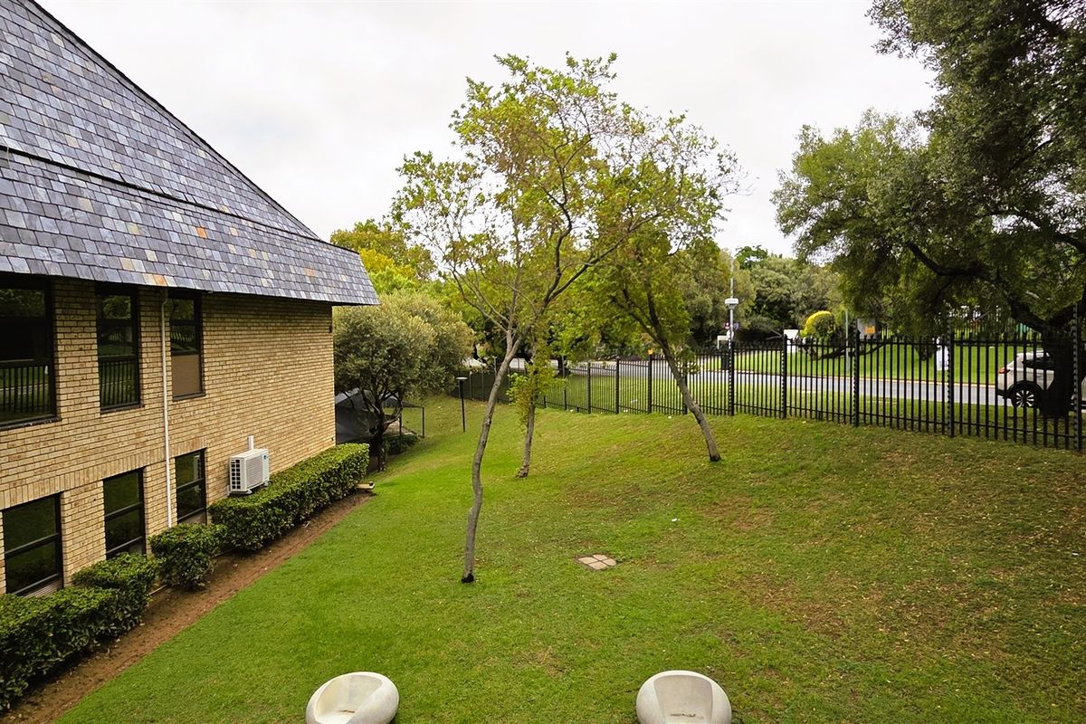 Exterior view of the office building featuring a brick facade, slate roof, and a well-maintained lawn area enclosed by perimeter fencing.
