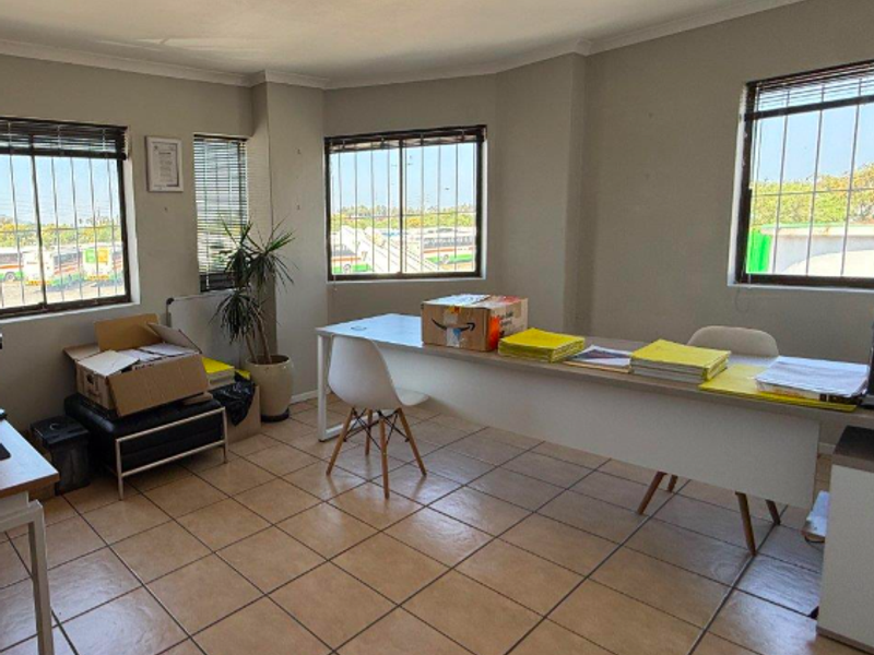 Functional office space featuring ceramic tiled flooring, large windows with security bars, and overhead fluorescent lighting.