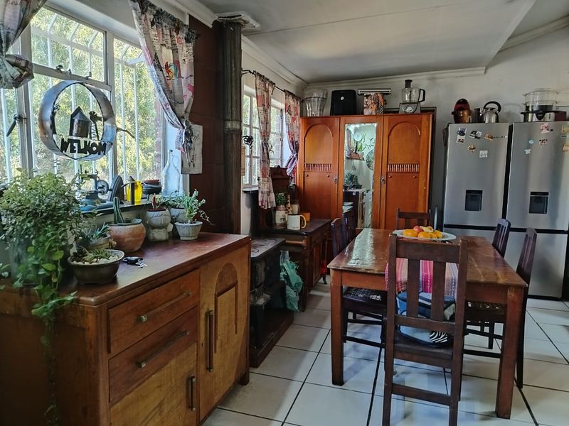 Open plan living and dining area featuring tiled flooring, metal window frames with security bars, and a wood burning stove.