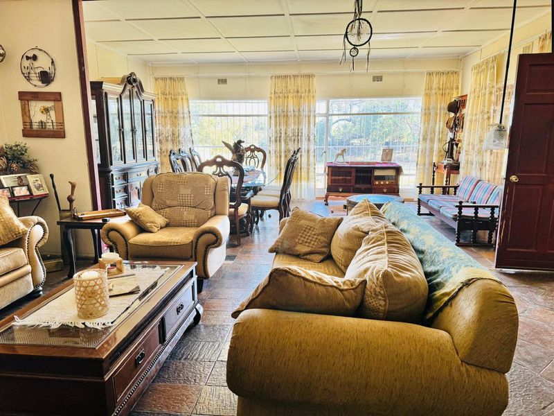 Spacious open-plan living and dining area featuring tiled flooring, large windows providing natural light, and a classic grid ceiling design.