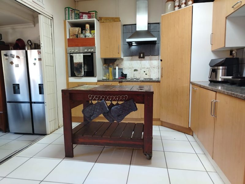 A functional kitchen featuring laminate cabinetry, built-in oven, stainless steel extractor fan, and tiled flooring, offering a practical layout for daily meal preparation.