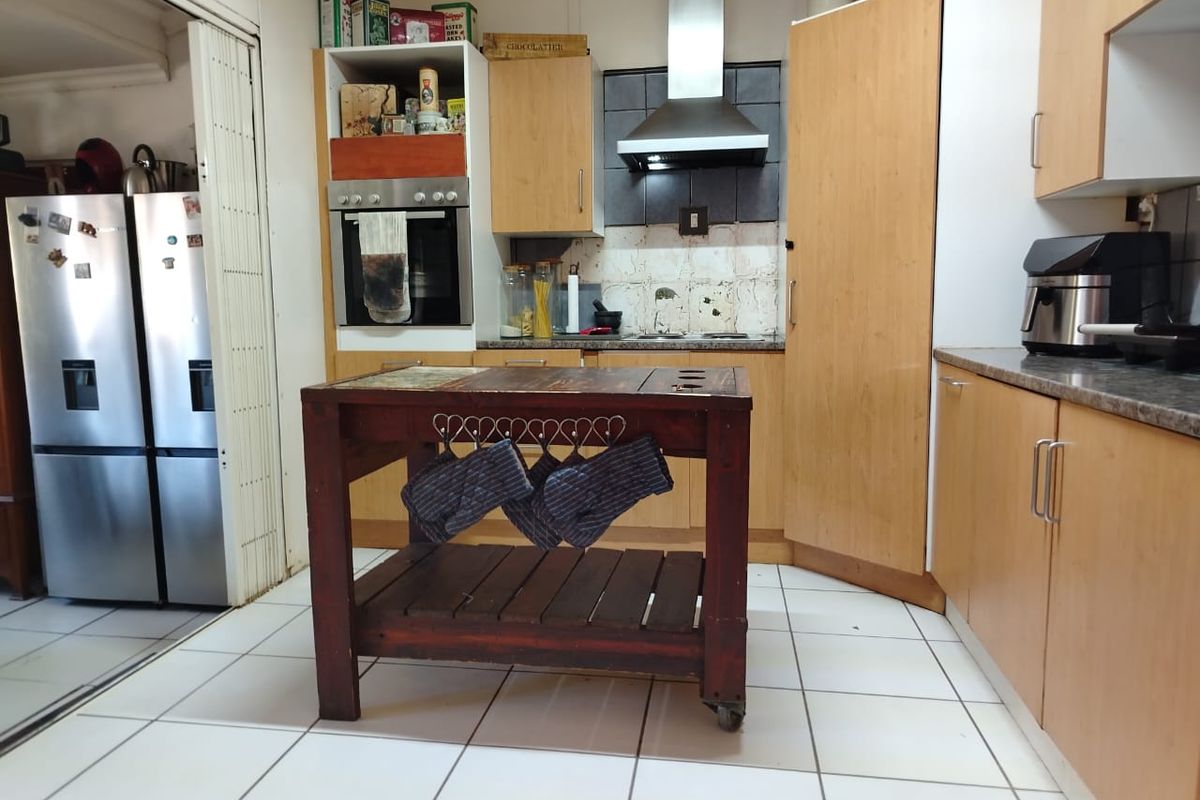 A functional kitchen featuring laminate cabinetry, built-in oven, stainless steel extractor fan, and tiled flooring, offering a practical layout for daily meal preparation.