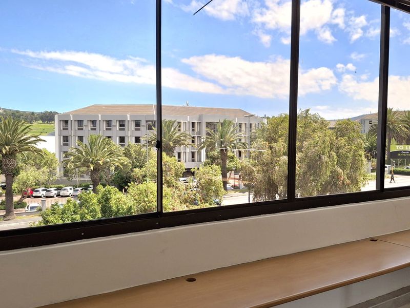 Bright office space featuring a large window with pleasant exterior views and a functional built-in desk.