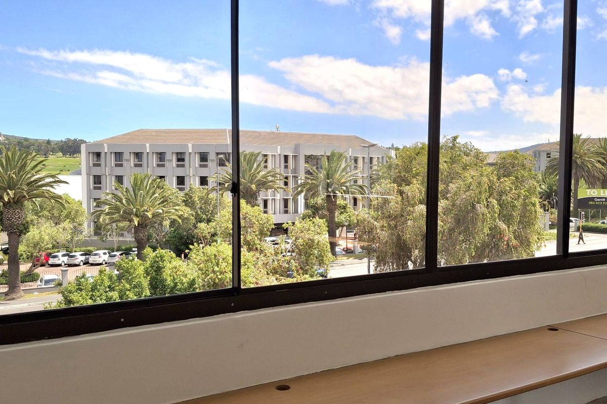 Bright office space featuring a large window with pleasant exterior views and a functional built-in desk.