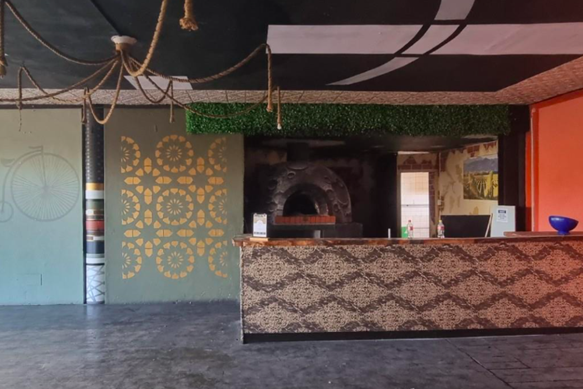 Restaurant kitchen area featuring a built-in pizza oven, service counter, and decorative wall finishes, providing a functional space for food preparation and service.