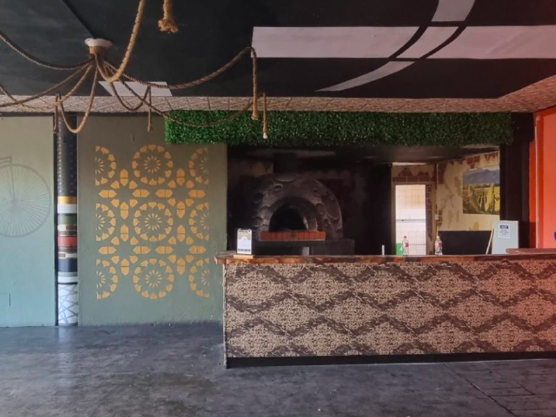 Restaurant kitchen area featuring a built-in pizza oven, service counter, and decorative wall finishes, providing a functional space for food preparation and service.