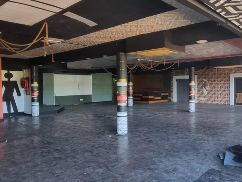 Spacious open-plan restaurant interior featuring structural columns, decorative ceiling panels, and a built-in service counter, currently vacant and ready for renovation.