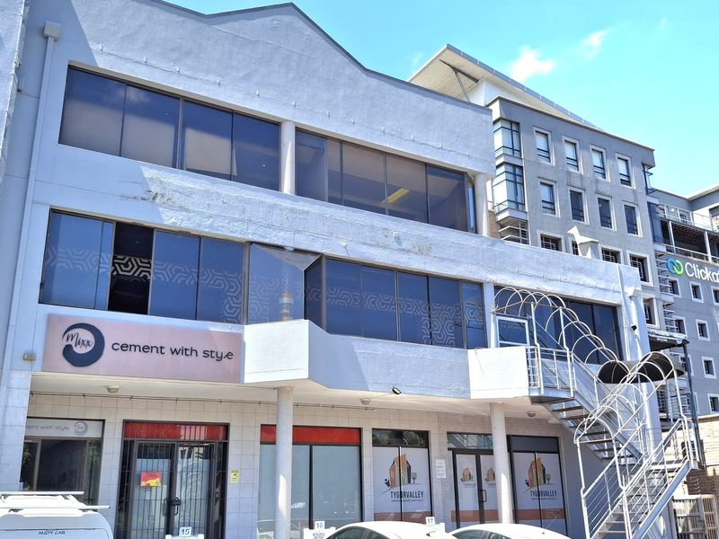 Front exterior view of a multi-story commercial building featuring large glass windows, an external metal staircase, and prominent signage.