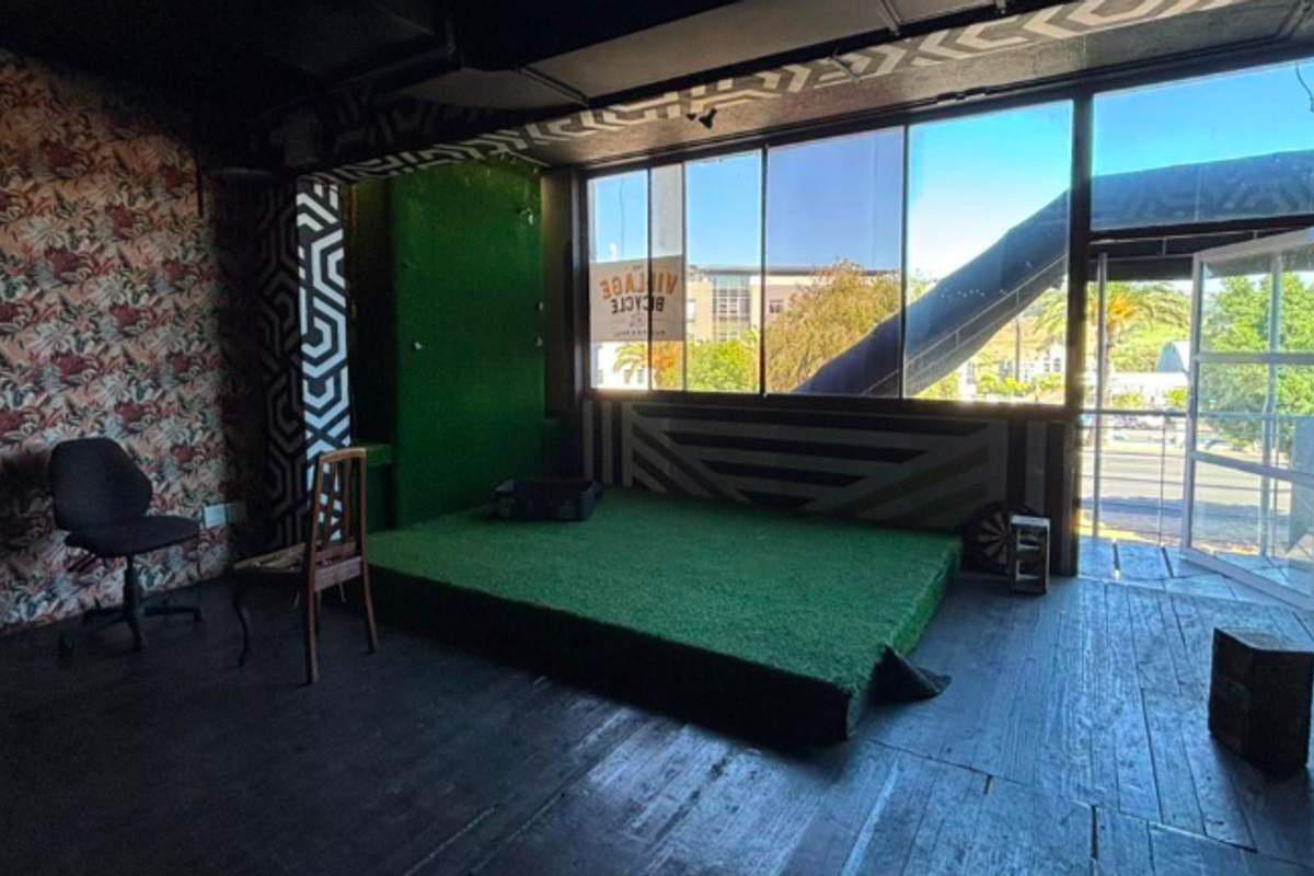 Spacious restaurant area featuring a raised platform with artificial grass, large windows providing natural light, and direct access to an outdoor space.