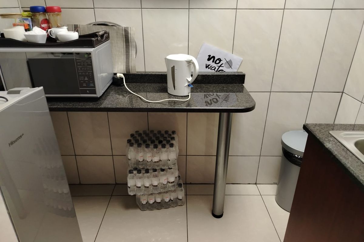 A functional kitchenette area featuring granite countertops, tiled walls, and floor, providing a compact space for basic food preparation and utility needs.