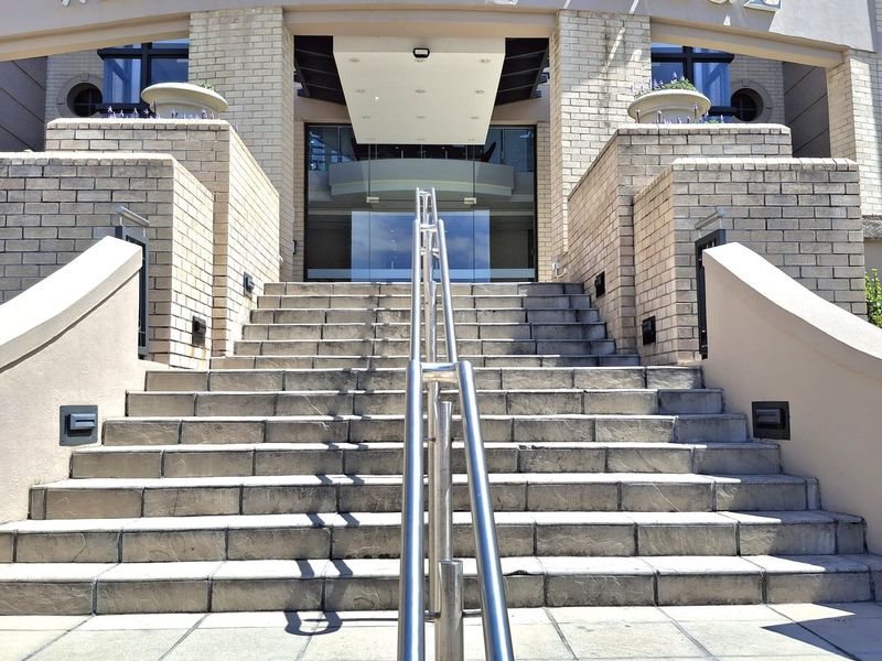 The grand entrance to Waterside Place features a wide stone staircase with a central stainless steel handrail leading to a modern glass doorway.