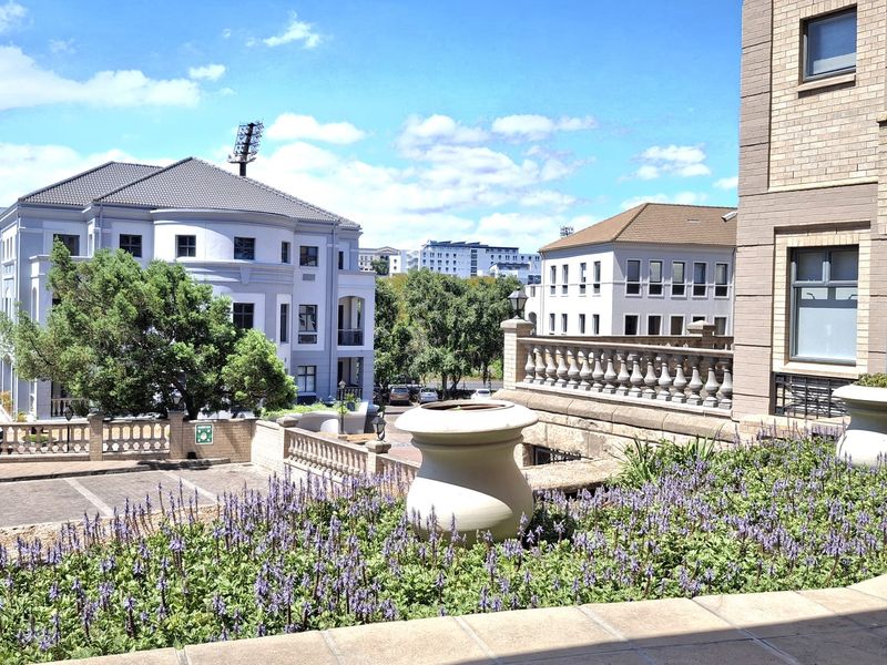 A view of the office complex exterior featuring a stone balustrade, tiled terrace area, and well-maintained landscaped garden beds.