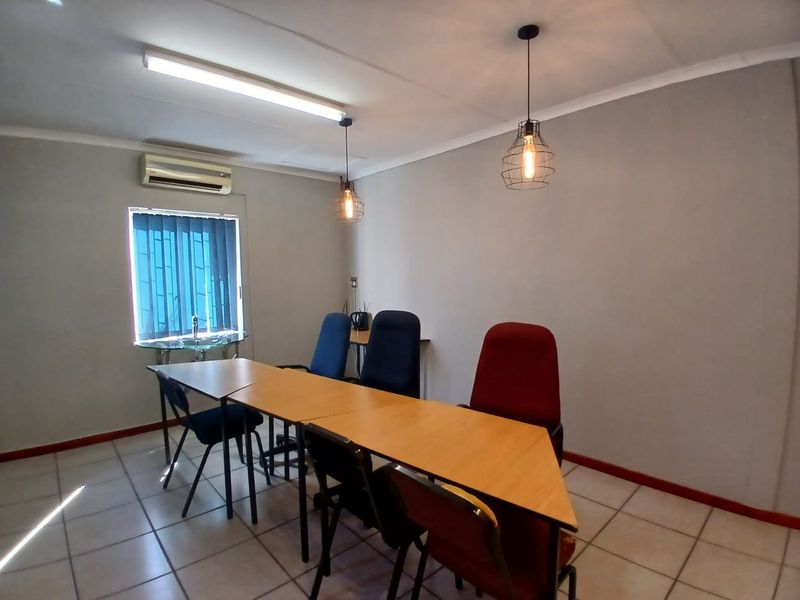 A functional office space featuring ceramic tile flooring, split-system air conditioning, and a mix of modern pendant and overhead lighting.