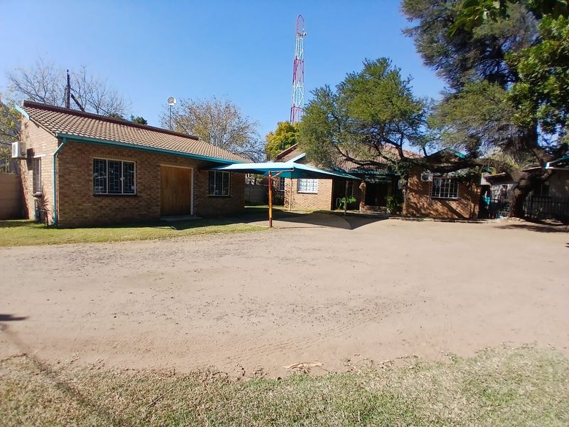 Front view of the office property featuring face brick construction, a tiled roof, and a covered carport area.