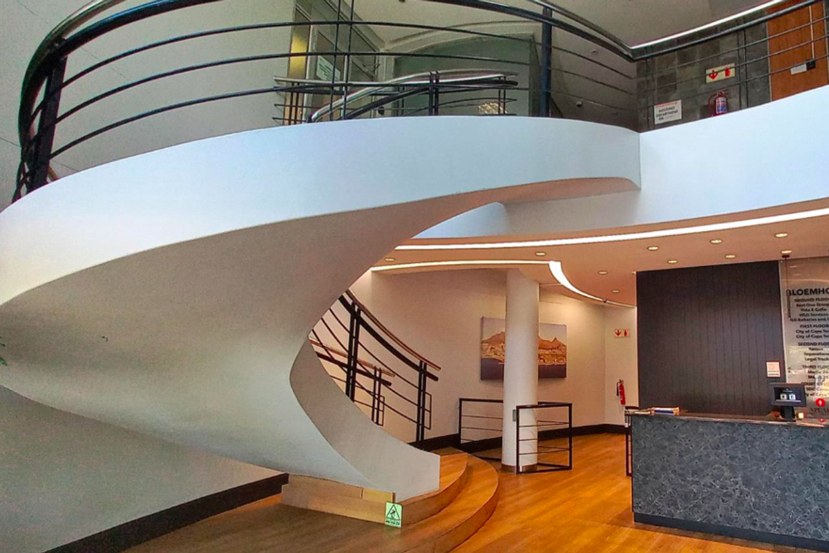 Modern office building entrance featuring a striking spiral staircase, reception desk, and high-quality finishes in a bright, professional lobby area.