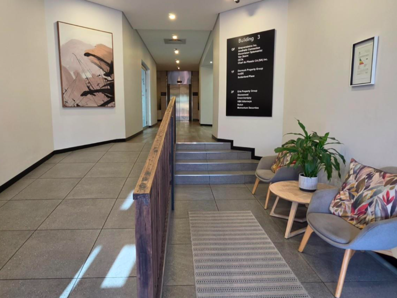 A modern, well-maintained office building entrance lobby featuring tiled flooring, a directory board, and elevator access.