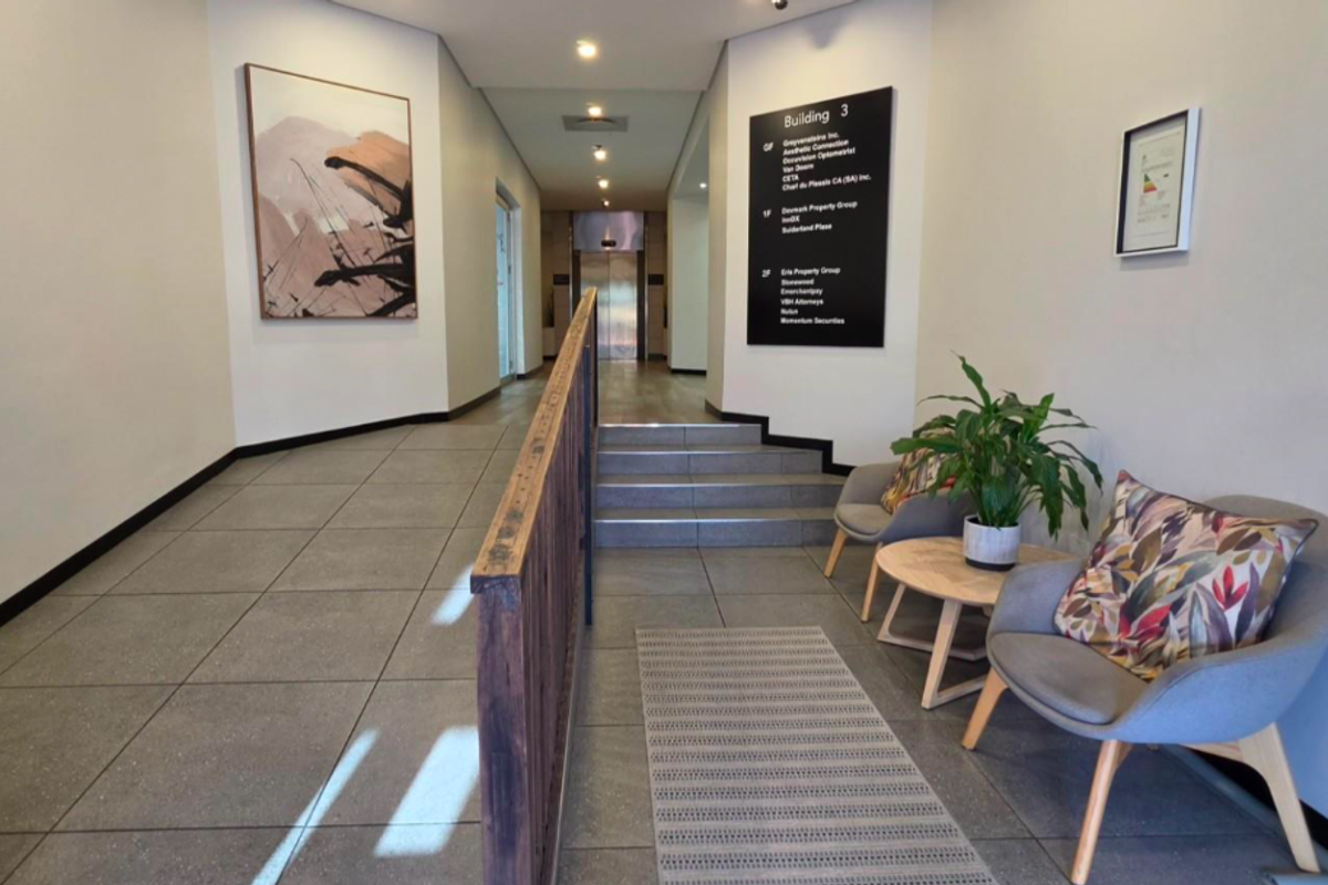 A modern, well-maintained office building entrance lobby featuring tiled flooring, a directory board, and elevator access.